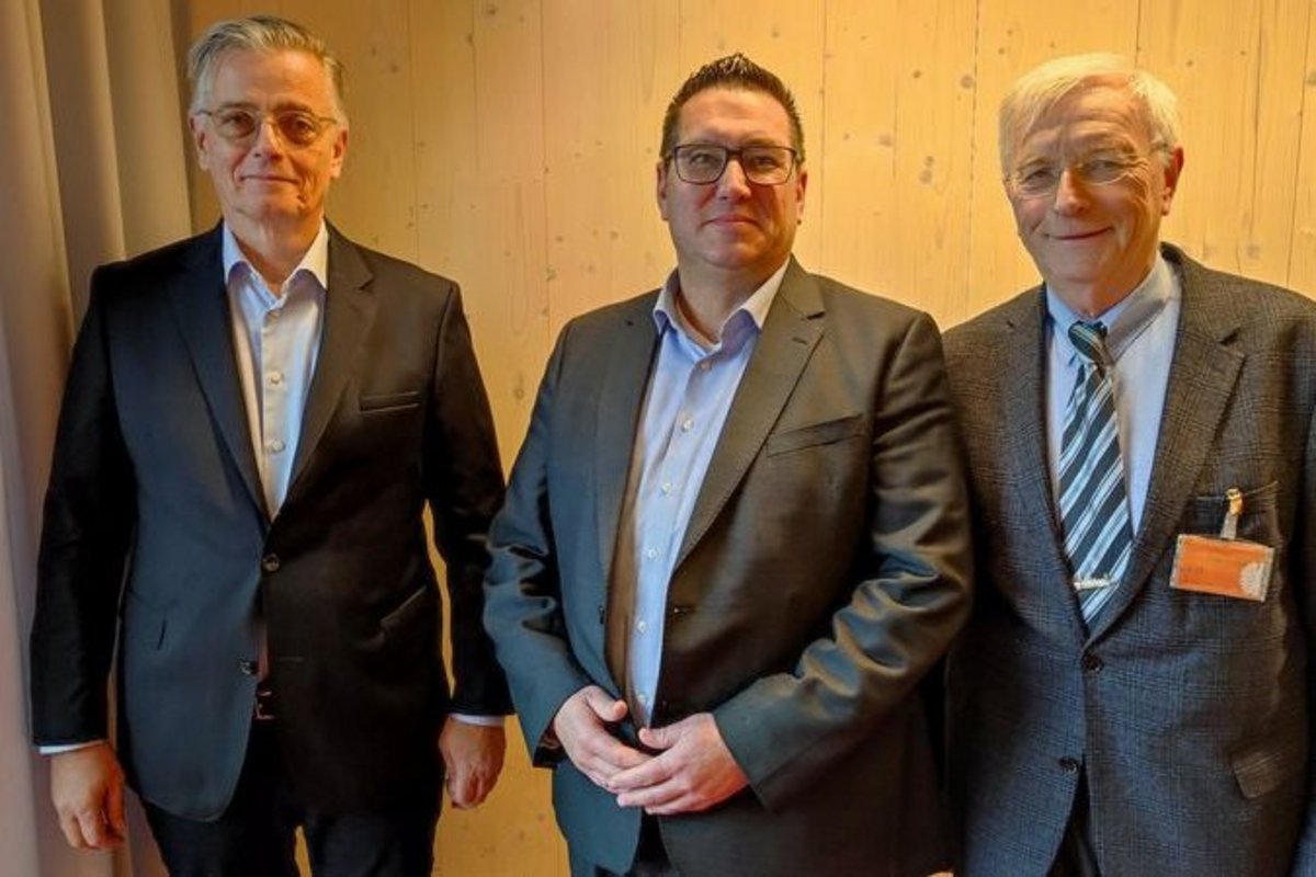 3 Männer in dunklen Anzügen im gelben Licht